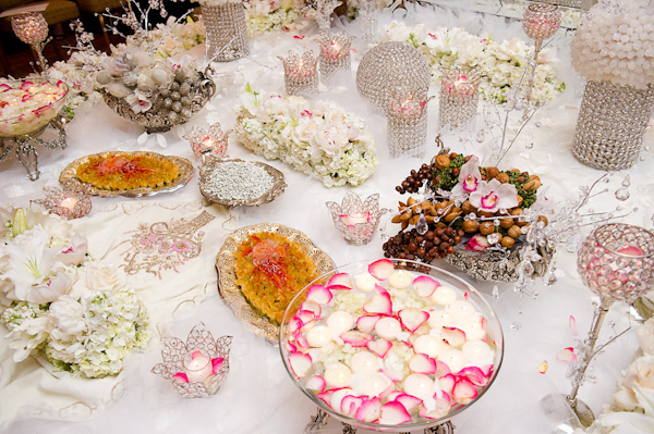 beautiful reception tabletop decor - crystal candle holders,vases, and punchbowls with pink, white, ivory, and green floral accessories - photo by Houston based wedding photographer Adam Nyholt